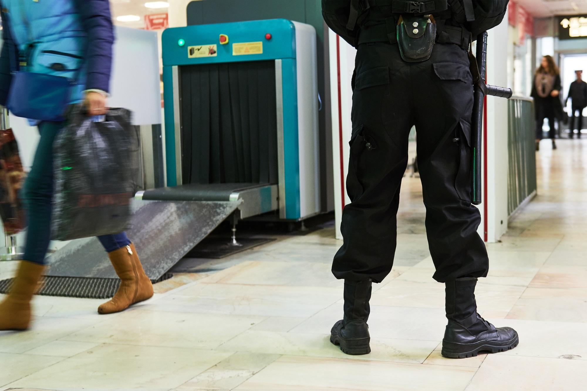 Un agent de sécurité a l'aéroport posant a côté du scanner à rayons X