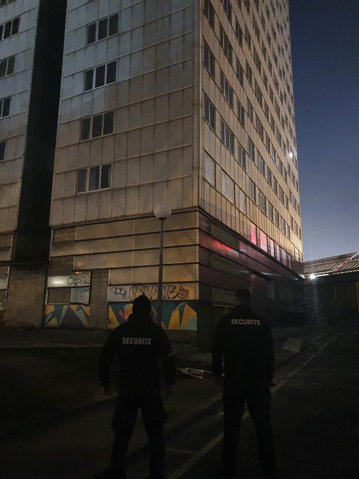 Deux agents de sécurités devant un immeuble aux graffitis