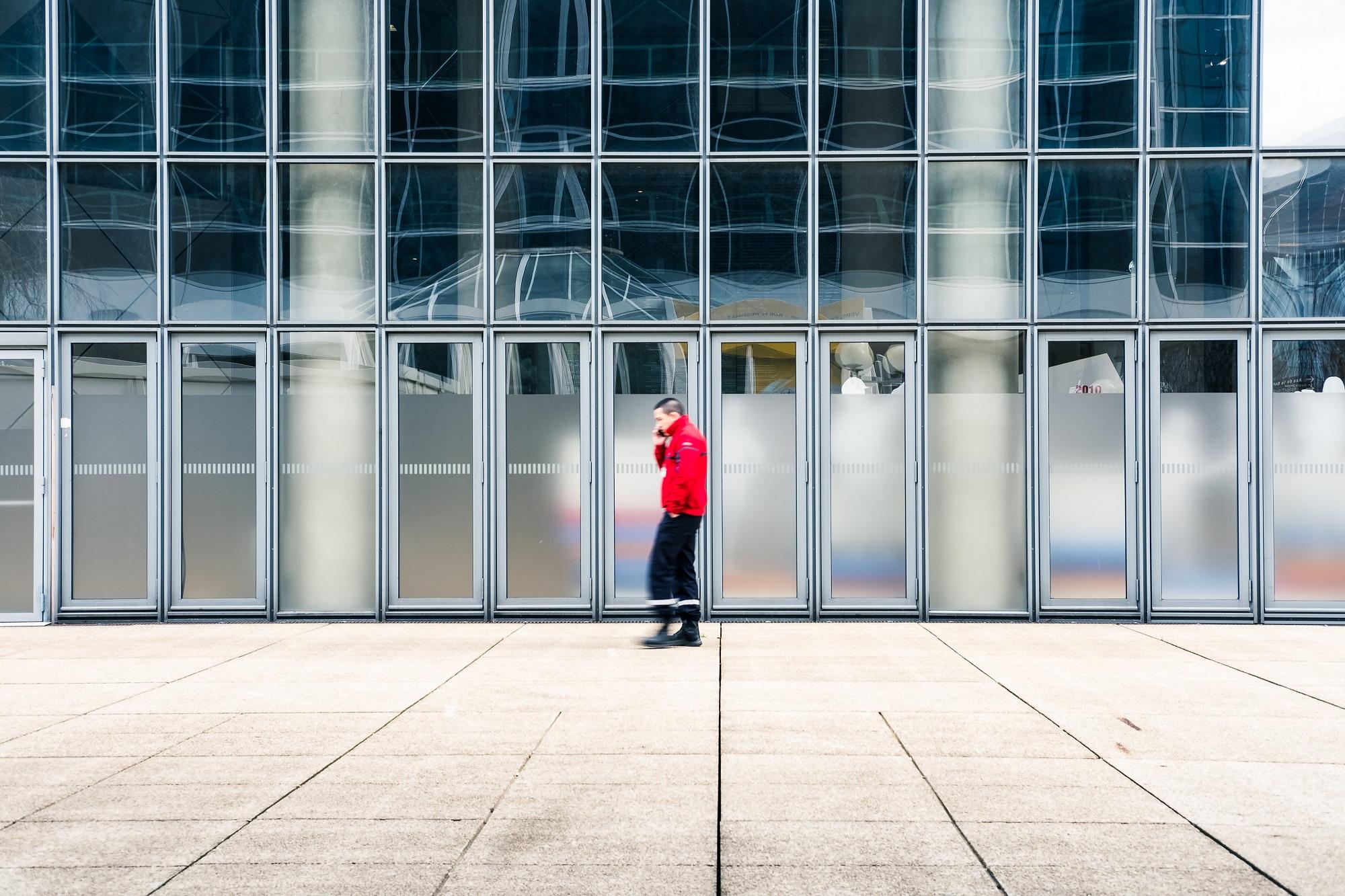 Un agent de sécurité incendie vêtu de son uniforme rouge devant un bâtiment vitré